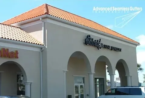Commercial storefront gutter installation with Advanced Seamless Gutters branding